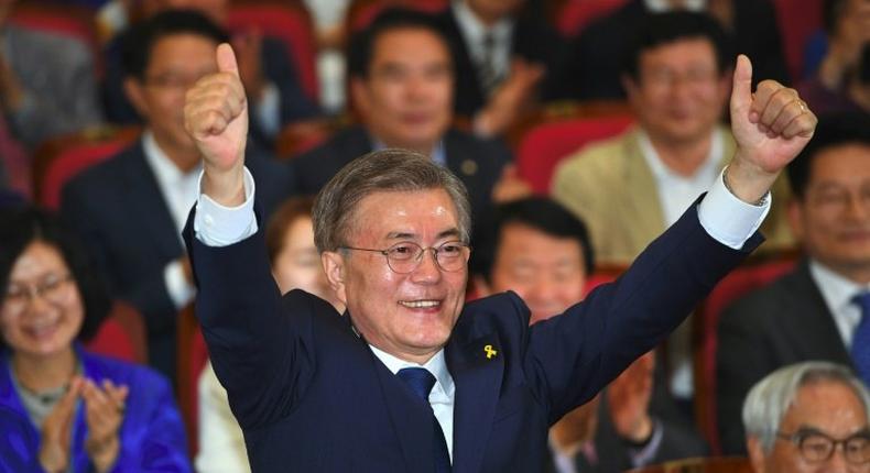 South Korean presidential candidate Moon Jae-in (C) gives the thumbs-up as he watches screens showing the result of exit polls of the presidential election at a hall of the National Assembly in Seoul on May 9, 2017