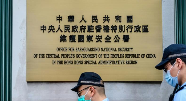 Police walk past a plaque outside the Office for Safeguarding National Security of the Central People's Government in the Hong Kong Special Administrative Region after its official inauguration