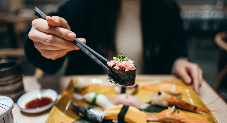 Young Asian woman eating freshly made sushi with side dish and green tea in a Japanese restaurant.Getty Images