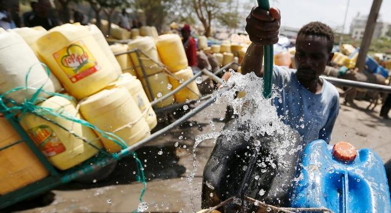 A man pours water into barrels for sale