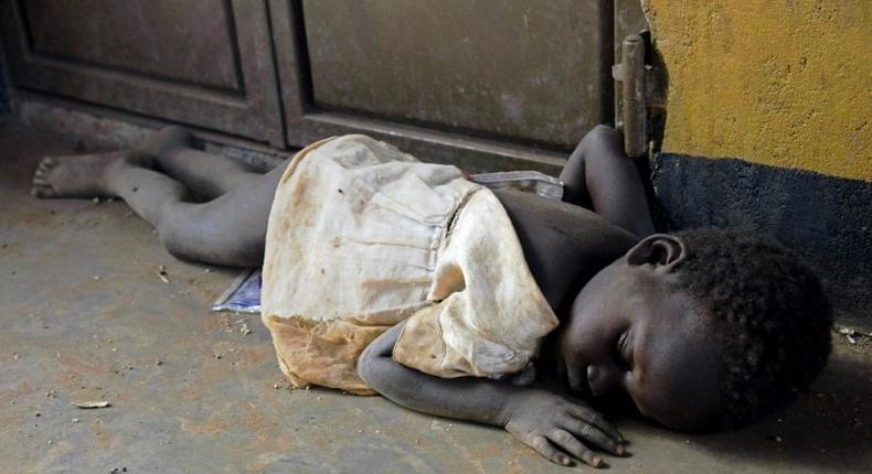 A newly arrived refugee child from South Sudan sleeps on a dirty floor on the Ugandan side of the Ngomoromo border post