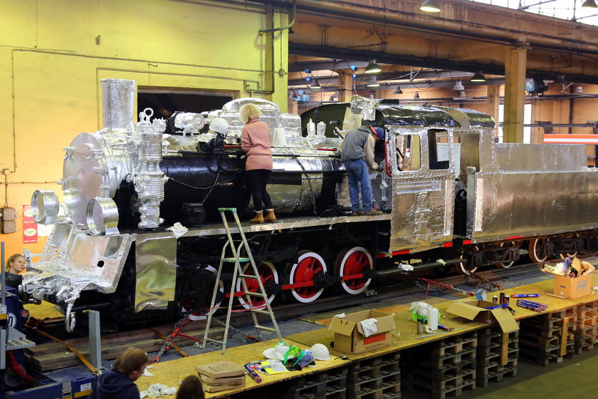 Oklejona folią aluminiową lokomotywa stanie przed dworcem Łódź Fabryczna