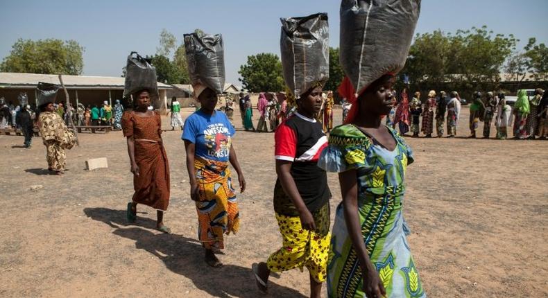 This photo taken on December 4, 2014 shows displaced women carrying sacks of food aid received during a distribution at the Cathedral of Yola, state capital of Adamawa 