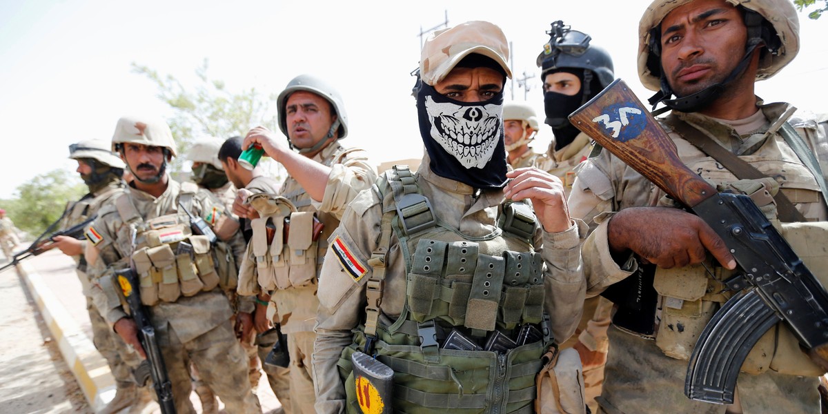 Iraqi army soldiers stand with their weapons in center of Fallujah.