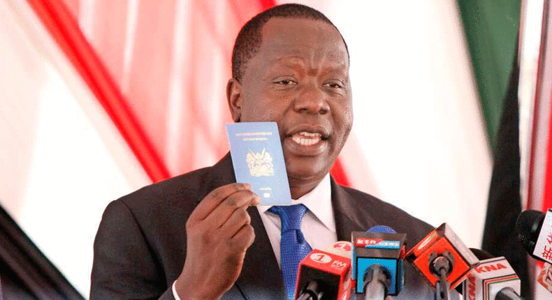 Interior CS Fred Matiang'i  holding a photo of the new EAC Passport
