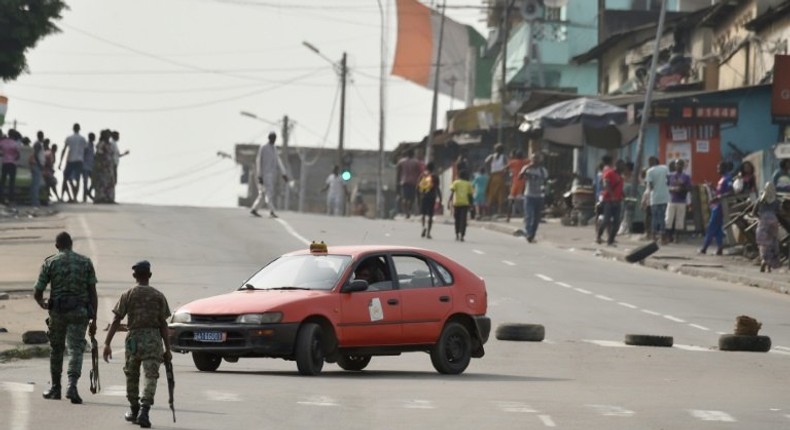 Soldiers stand guard at a road black in the Plateau business district of Abidjan on January 7, 2017, as shots were heard inside a nearby military camp according to local media