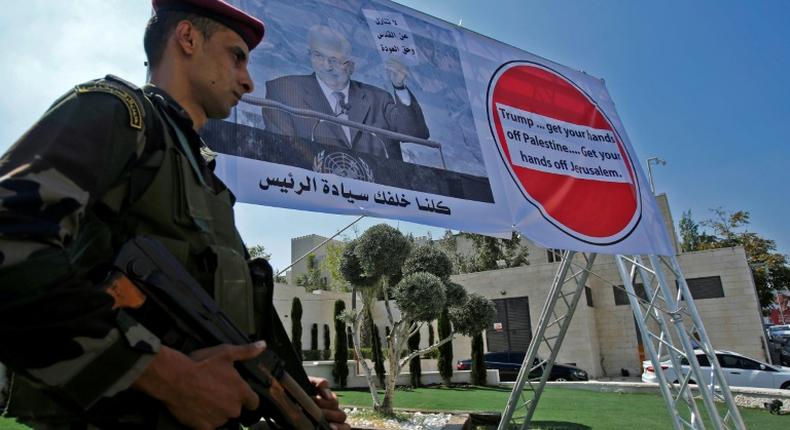 A member of the Palestinian security forces stands in front of a poster of President Mahmud Abbas, during a protest in Bethlehem on September 26, 2018 against Washington's decision to cut aid
