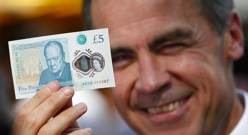 Bank of England Governor Mark Carney holds a new plastic £5 note as he visits Whitecross Street market in London.