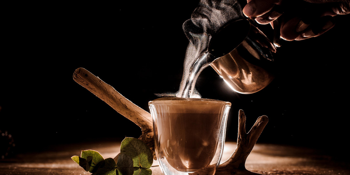 Male hand pouring water from pitcher into the coffee cup