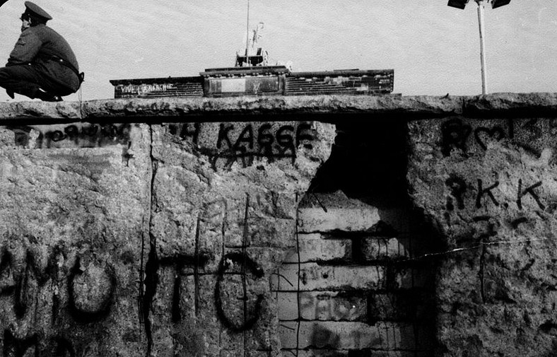 Częściowo zniszczony mur przy Bramie Brandenburskiej; żołnierz pilnujący pozostałości, listopad 1989