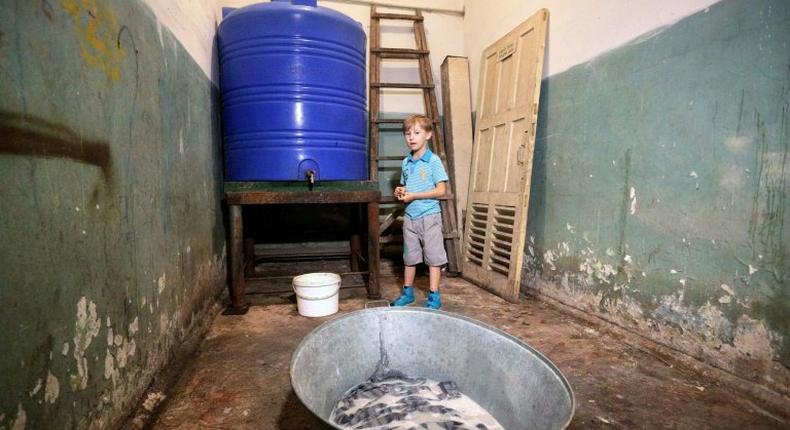 Sasha, 10, stands in a bomb shelter in Donetsk, eastern Ukraine, on September 19, 2016, where he hides with his mother Elena