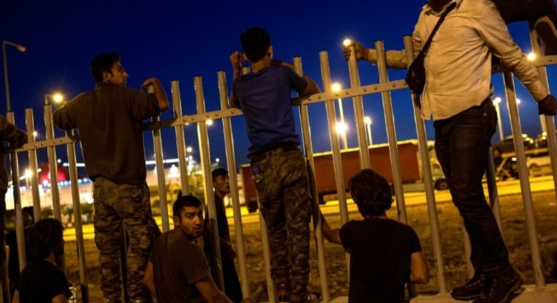 Migrants try to jump over a fence into a ferry terminal in Patras, southwestern Greece, on June 20, 2017