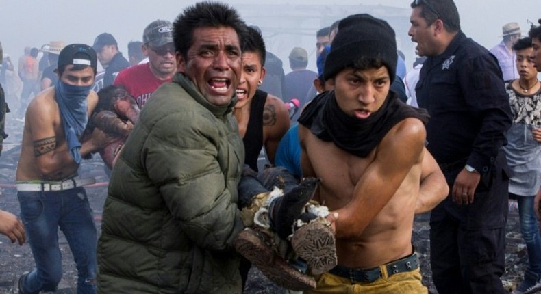 Victims are led away from the smoldering ruins of a fireworks market in Mexico City