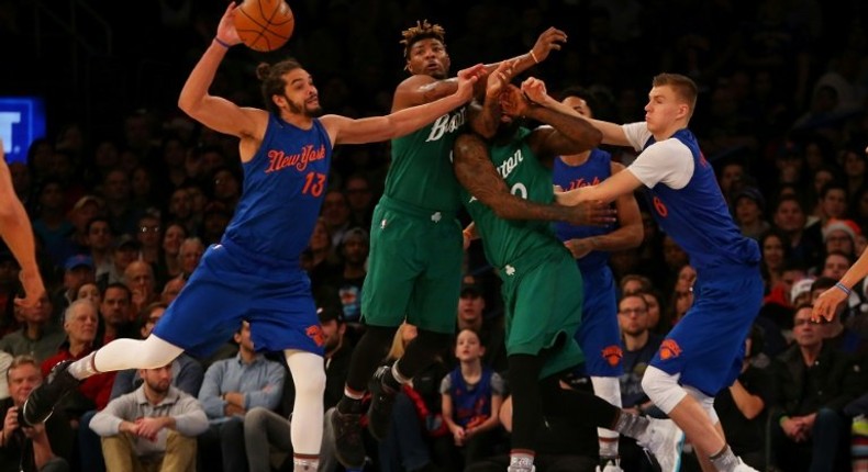 Joakim Noah and Kristaps Porzingis of the New York Knicks pursue the loose ball against Marcus Smart and Amir Johnson of the Boston Celtics at Madison Square Garden on December 25, 2016