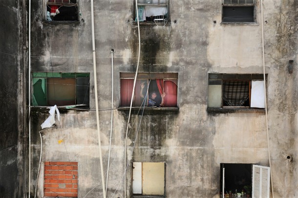 Edilson, a member of Brazil's Movimento dos Sem-Teto (Roofless Movement), poses in the window of his