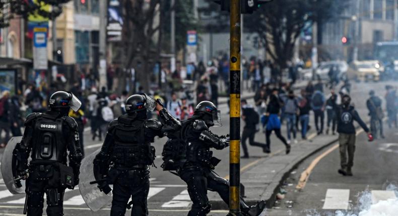 A riot policeman kicks a tear-gas canister during an anti-government protest in Bogota on November 23, 2019