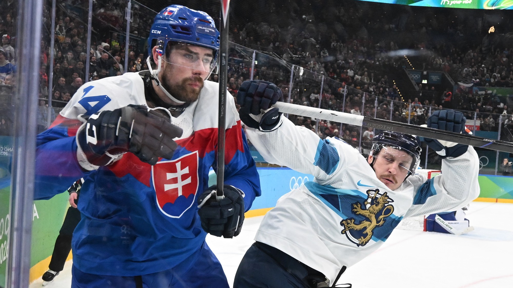 Slovenský hokejista Peter Čerešnák (14) a hráč Fínska bojujú o puk. 