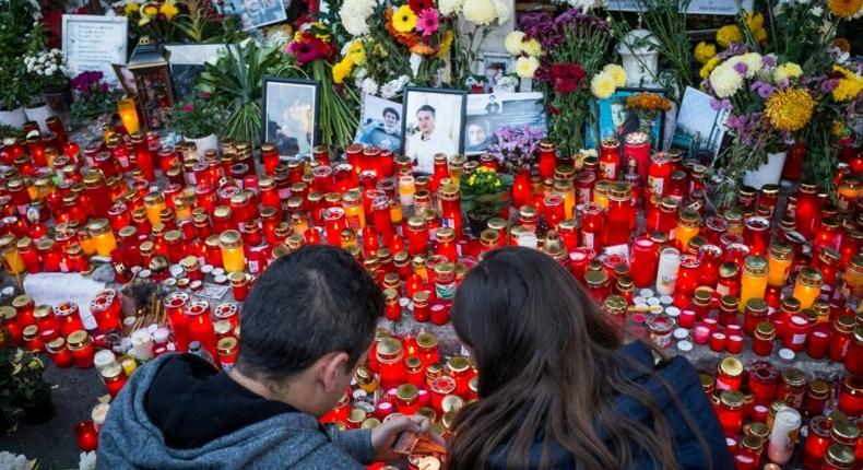 A couple lights candles at the end of a march in the memory of the 64 people who were killed one year ago when Colectiv club caught fire during a rock concert, on October 30, 2016 in Bucharest