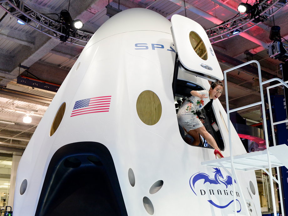 A woman steps out of a Dragon capsule model during a 2014 SpaceX event.