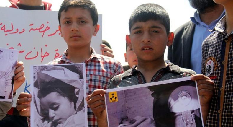 Syrian residents of Khan Sheikhun hold placards and pictures on April 7, 2017 during a protest condemning a suspected chemical weapons attack on their town that killed at least 86 people