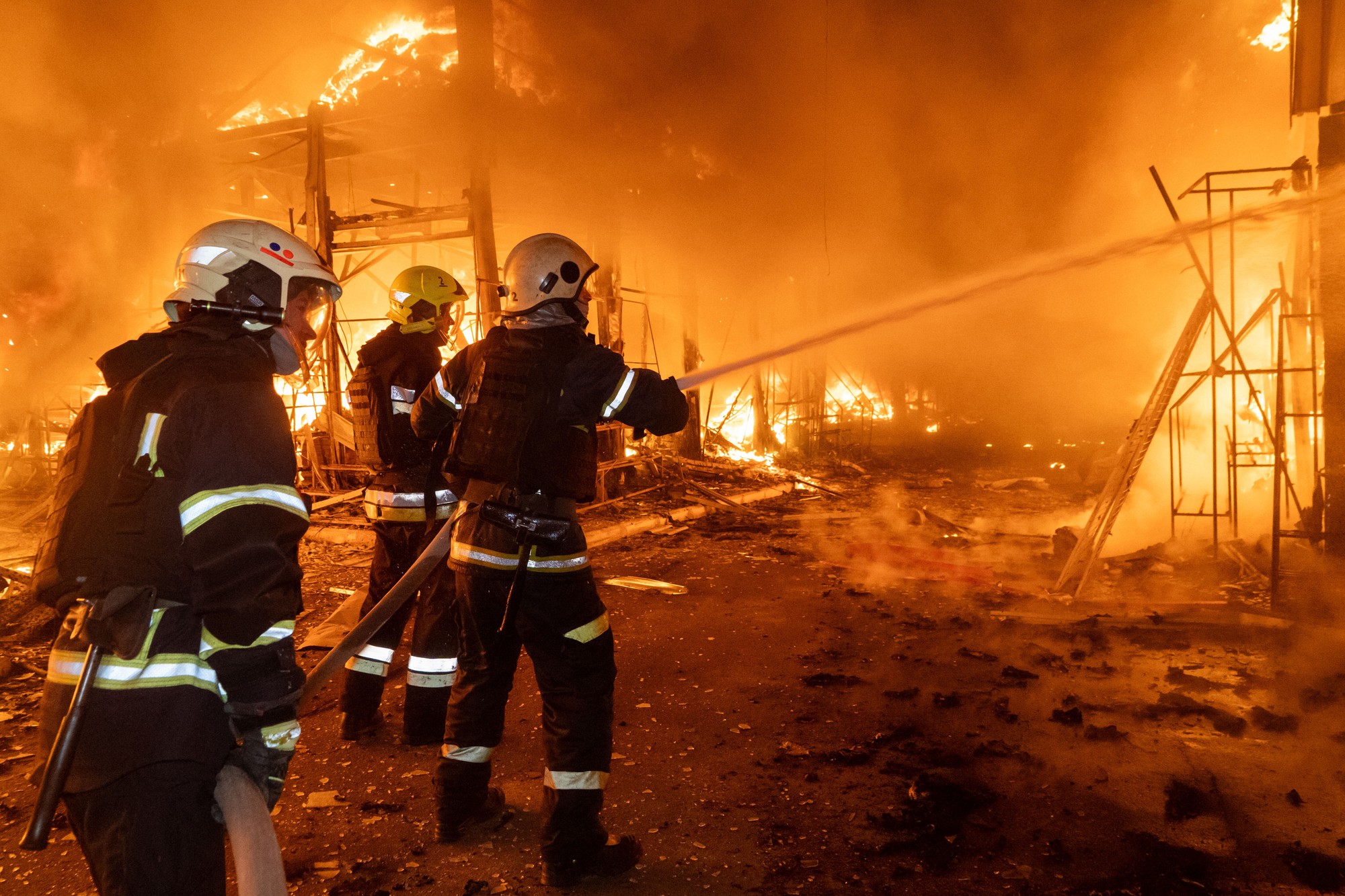 Hasiči bojujú s požiarom po ruskom leteckom útoku, ktorý zasiahol trh Barabašovo v Charkove.