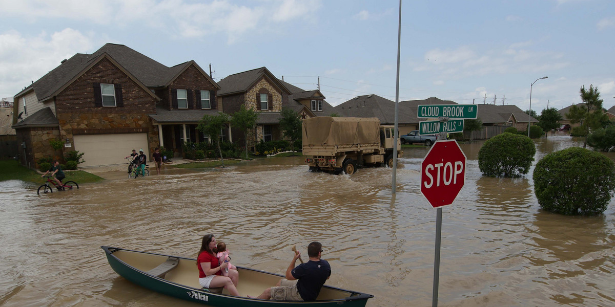 A woman holds a baby in a canoe as Texas Guardsmen arrive to assist after flooding in Brookshire, Texas, U.S. April 20, 2016.