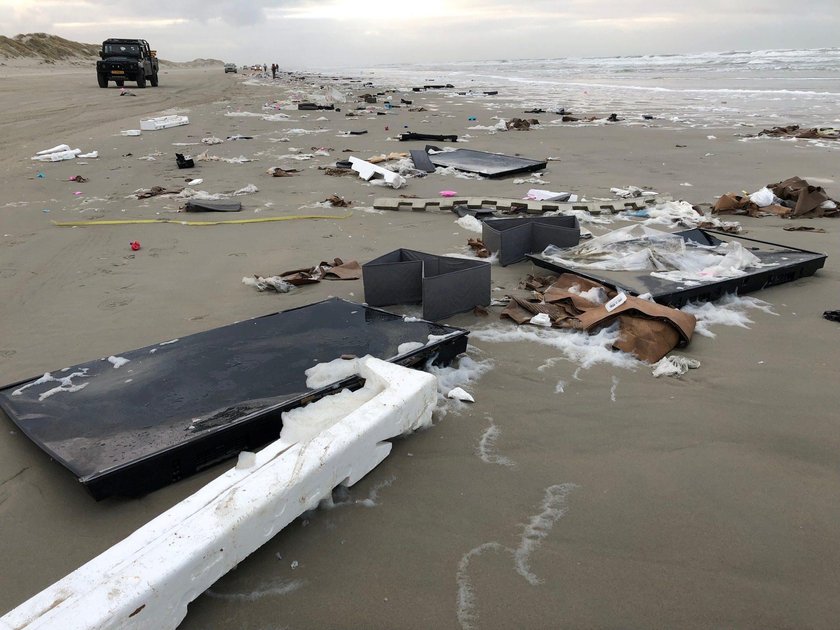 Person carries TV after it washed up on a beach in Terschelling