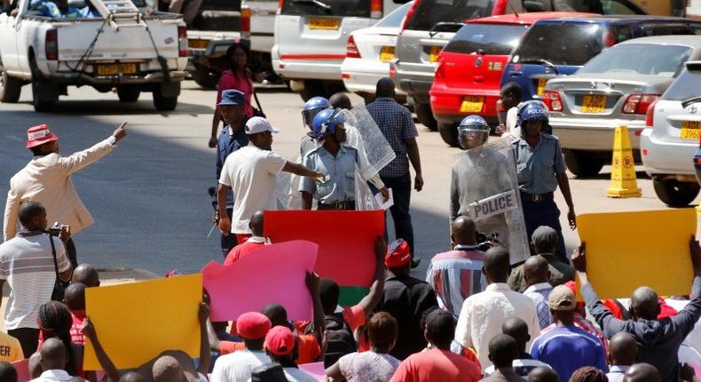 Locals hold placards during a protest by opposition youths who were demonstrating against alleged brutality by security agents in the capital Harare, Zimbabwe August 24, 2016. 