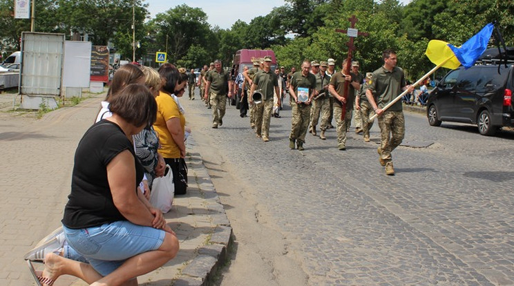 Térdelő gyászolók mellett kísérnek utolsó útjára egy kárpátaljai hősi halottat  Ilosva település főutcáján  Fotó: Facebook