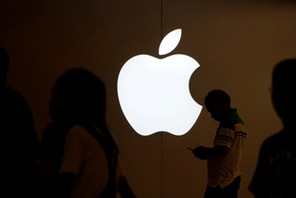 FILE PHOTO: A man looks at the screen of his mobile phone in front of an Apple logo outside its store in Shanghai