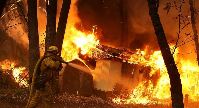 A Cal Fire firefighter monitors a burning home as the Camp Fire moves through the area on November 9, 2018 in Magalia, California. Fueled by high winds and low humidity, the rapidly spreading Camp Fire ripped through the town of Paradise and quickly charred 70,000 acres and destroyed numerous homes and businesses in a matter of hours.