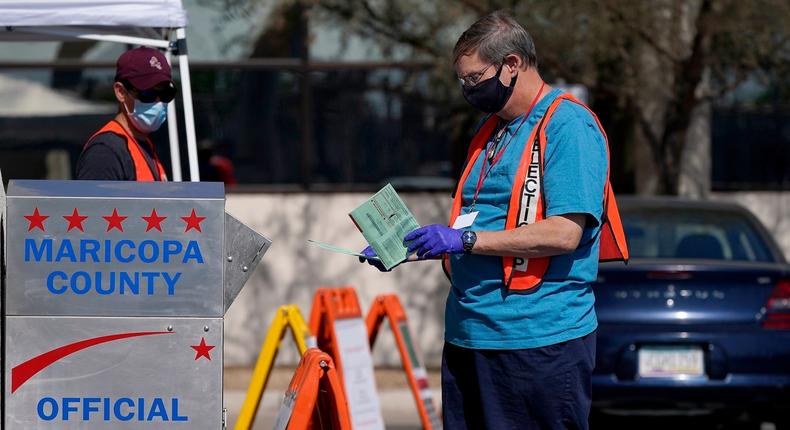 Volunteers help voters as voters drop off their ballots at the Maricopa County Recorder's Office Tuesday, Oct. 20, 2020, in Phoenix. In Arizona, Maricopa County, the nation's second-largest voting jurisdiction, a steady stream of cars go in and out of the parking lot to deliver ballots at the drop box location.
