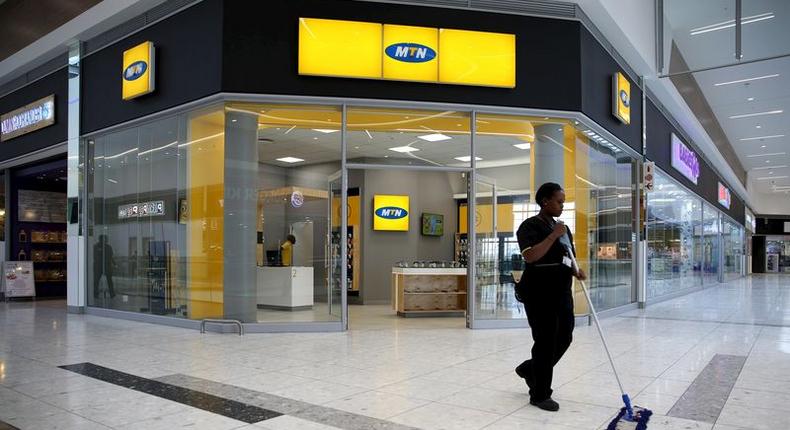 A worker sweeps past an outlet of South Africa's MTN Group in Johannesburg, February 23, 2016. 