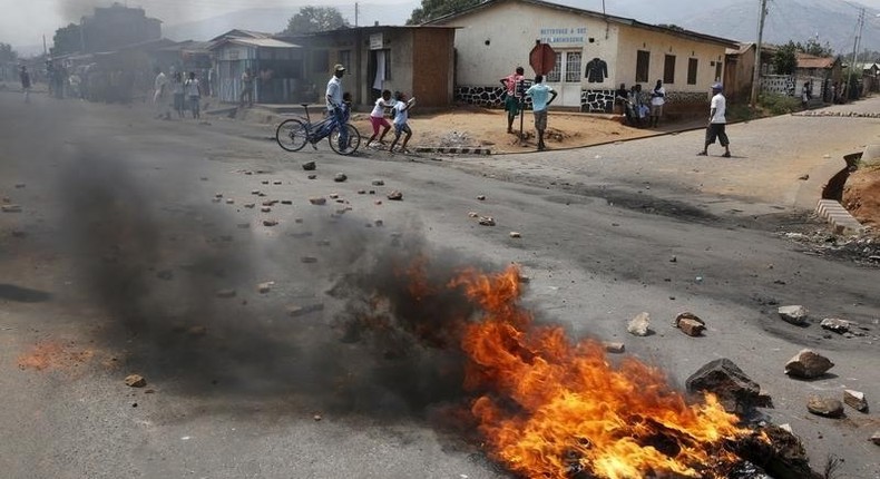 Residents move past a burning barricade on a rock strewn street in Bujumbura's Niyakabiga district on Presidential election day in Burundi, July 21, 2015. REUTERS/Mike Hutchings