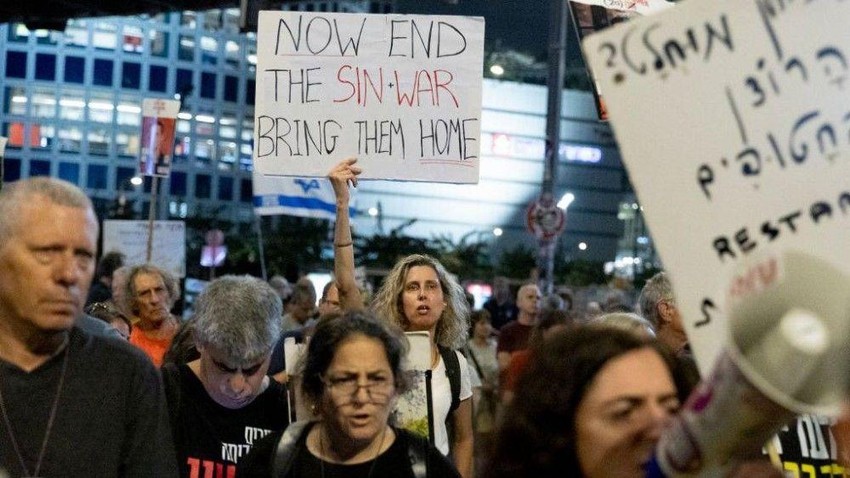Demonstrantkinja u Izraelu drži transparent sa igrom reči imena ubijenog vođe Hamasa: Sada kad je okončan Sin-war (rat), vrati ih kući“. | Foto: Getty Images