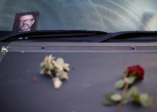 A photograph and rose lie on a car in tribute to singer George Michael outside of his home in north 