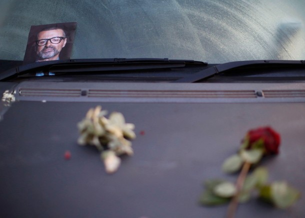 A photograph and rose lie on a car in tribute to singer George Michael outside of his home in north 