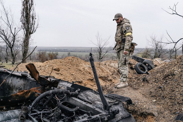Ukraiński żołnierz przy zniszczonym czołgu przed byłą bazą wojsk rosyjskich w wyzwolonym mieście Snihuriwka