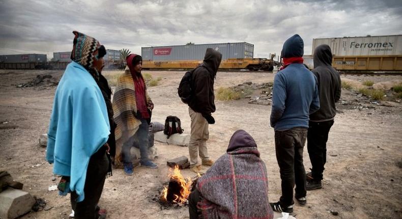 Migrants warm themselves next to a campfire near train tracks in Sonora state, Mexico close to the border with the United States