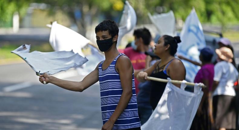 People flutter improvised white flags along a road to show their need for food during a mandatory quarantine imposed by the government against the spread of the new coronavirus in San Pedro Perulapan, El Salvador on June 10, 2020