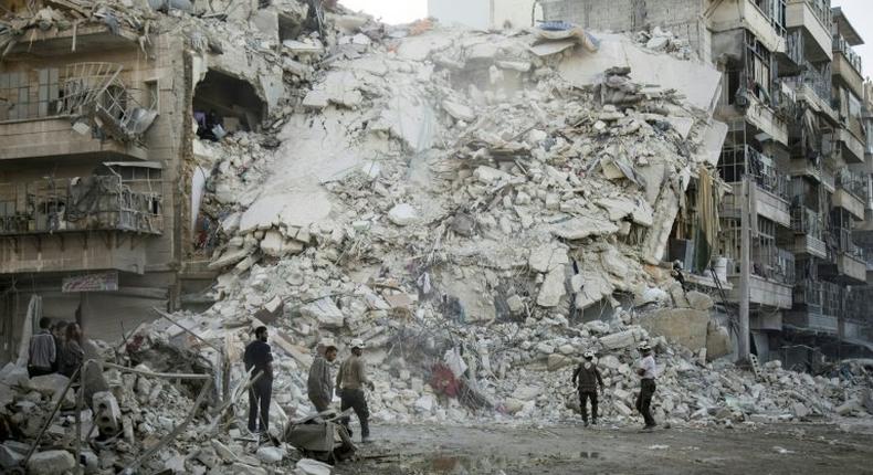 Members of the White Helmets search for victims amid the rubble of a destroyed building following reported air strikes in Aleppo, on October 17, 2016