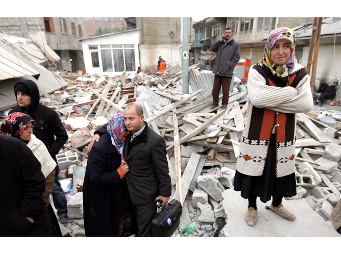 Pogrążone w żałobie rodziny ofiar trzęsienia ziemi na tle ruin domu. 25 października, trzęsienie ziemi o sile 7.2 w skali Richtera nawiedziło miasto Eris we wschodniej Turcji, zabijając setki osób i niszcząc tysiące domów