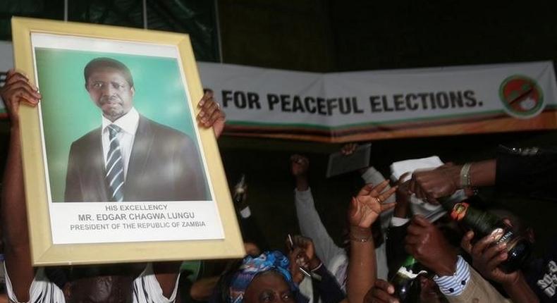 Patriotic Front General Secretary Davies Chama (L) celebrates while holding a portrait of President Edgar Chagwa Lungu after Lungu narrowly won re-election on Monday, in a vote his main rival Hakainde Hichilema rejected on claims of alleged rigging by the electoral commission, in the capital, Lusaka, Zambia, August 15, 2016. 