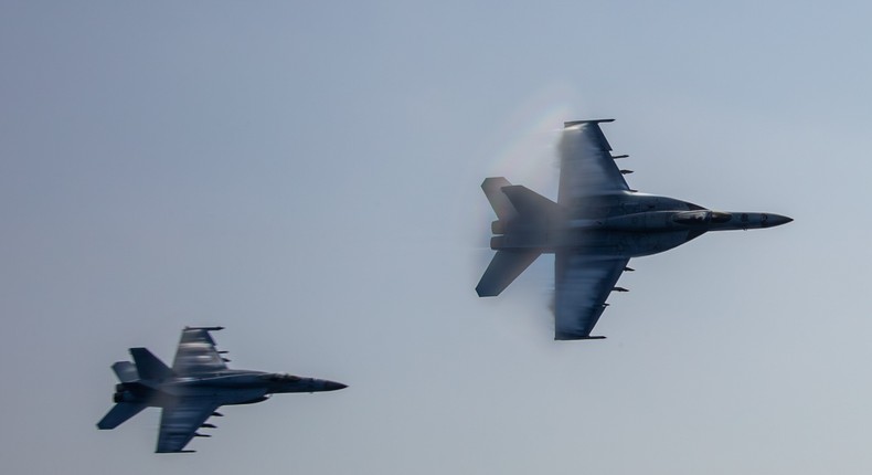 Two F/A-18E Super Hornets fly by the aircraft carrier USS Abraham Lincoln in September. The Lincoln has been deployed to the Middle East for several weeks.Us Navy photo