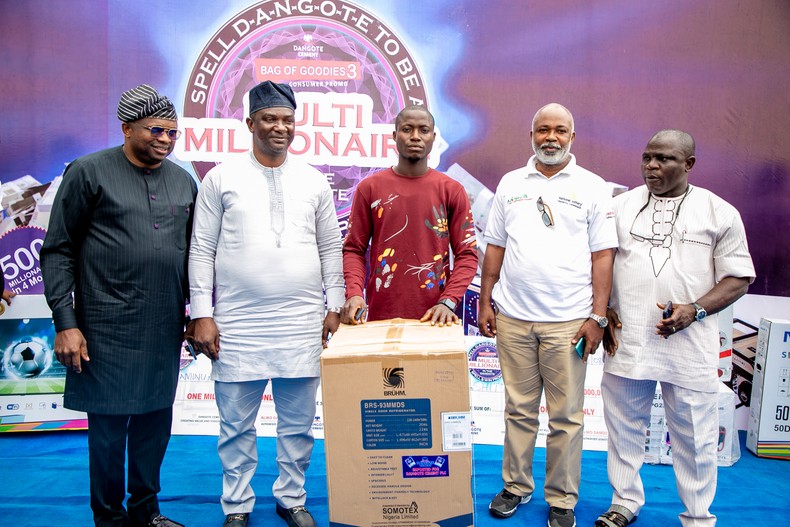 Winner of an instant prize of refrigerator flanked by guests and regulatory officials.