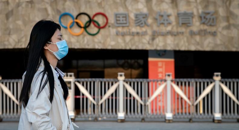 Passers-by at Beijing's Olympic Park wear protective face masks as the coronavirus pandemic causes problems around the world