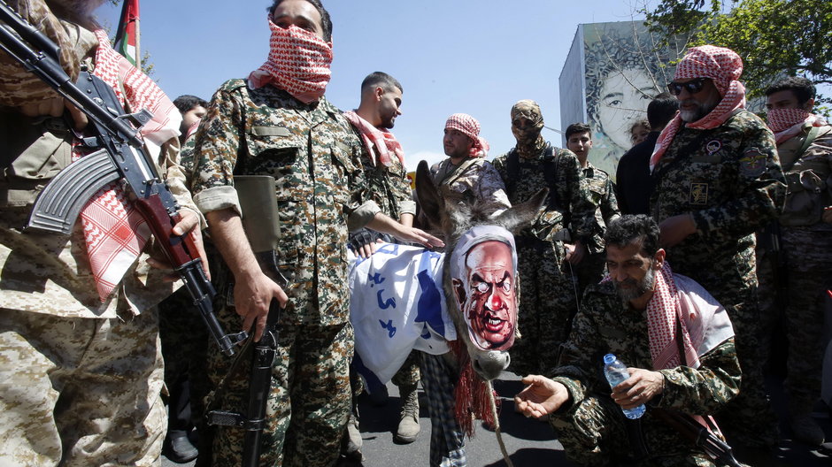 Uzbrojeni członkowie irańskich sił paramilitarnych (Basij) paradują z osłem okrytym izraelską flagą i noszącym maskę przedstawiającą karykaturę izraelskiego premiera Benjamina Netanjahu