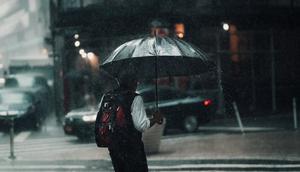 A man under an umbrella in rainy weather [Image Credit: Lerone Pieters]