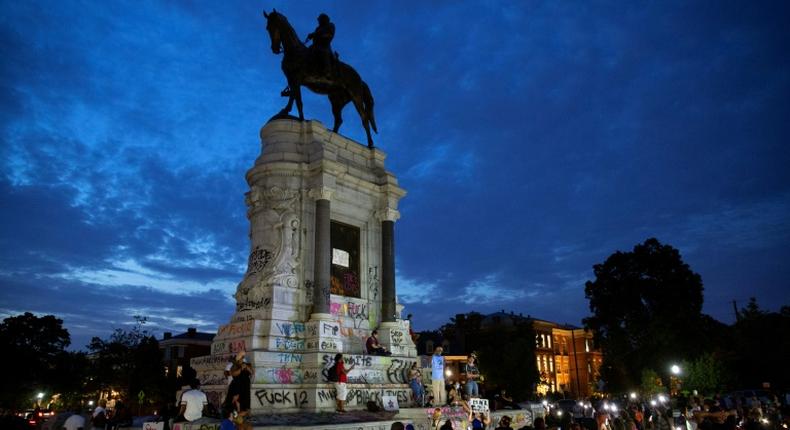 Protestors surround the statue of Confederate general Robert E. Lee in Richmod which the Virginia governor announced would be removed 'as soon as possible'