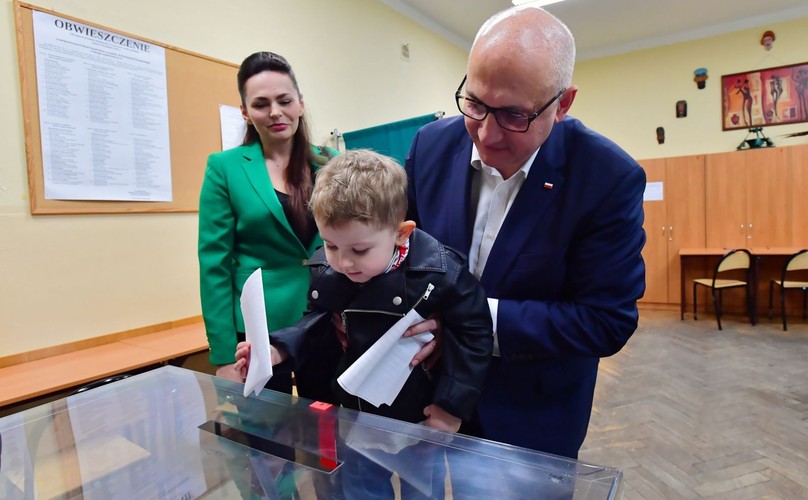Minister spraw wewnętrznych i administracji Joachim Brudziński (P) z żoną Arlettą (L) i synem Ignacym głosują w lokalu wyborczym w Szczecinie